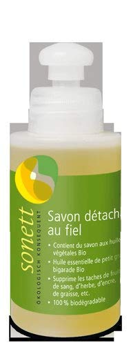 Petit flacon de savon détachant liquide posé sur du lin écru dans une buanderie