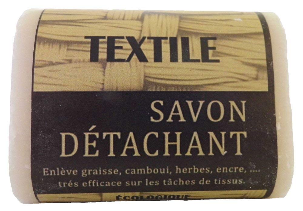 Trois pains de savon détachant au fiel de bœuf posés sur du lin dans une buanderie sobre.